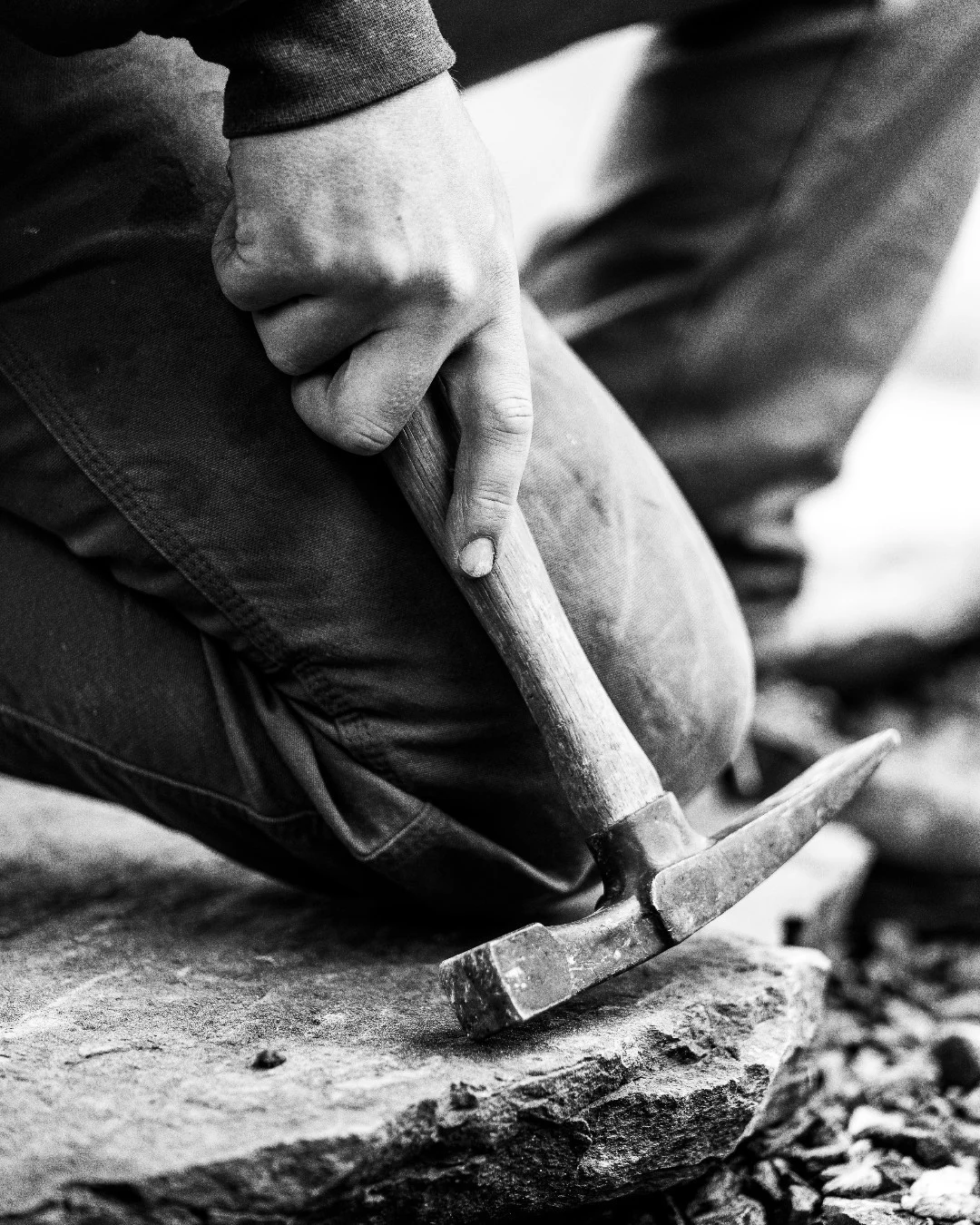 Close-up of Ty Garon’s hand gripping a mason’s hammer against a stone slab.