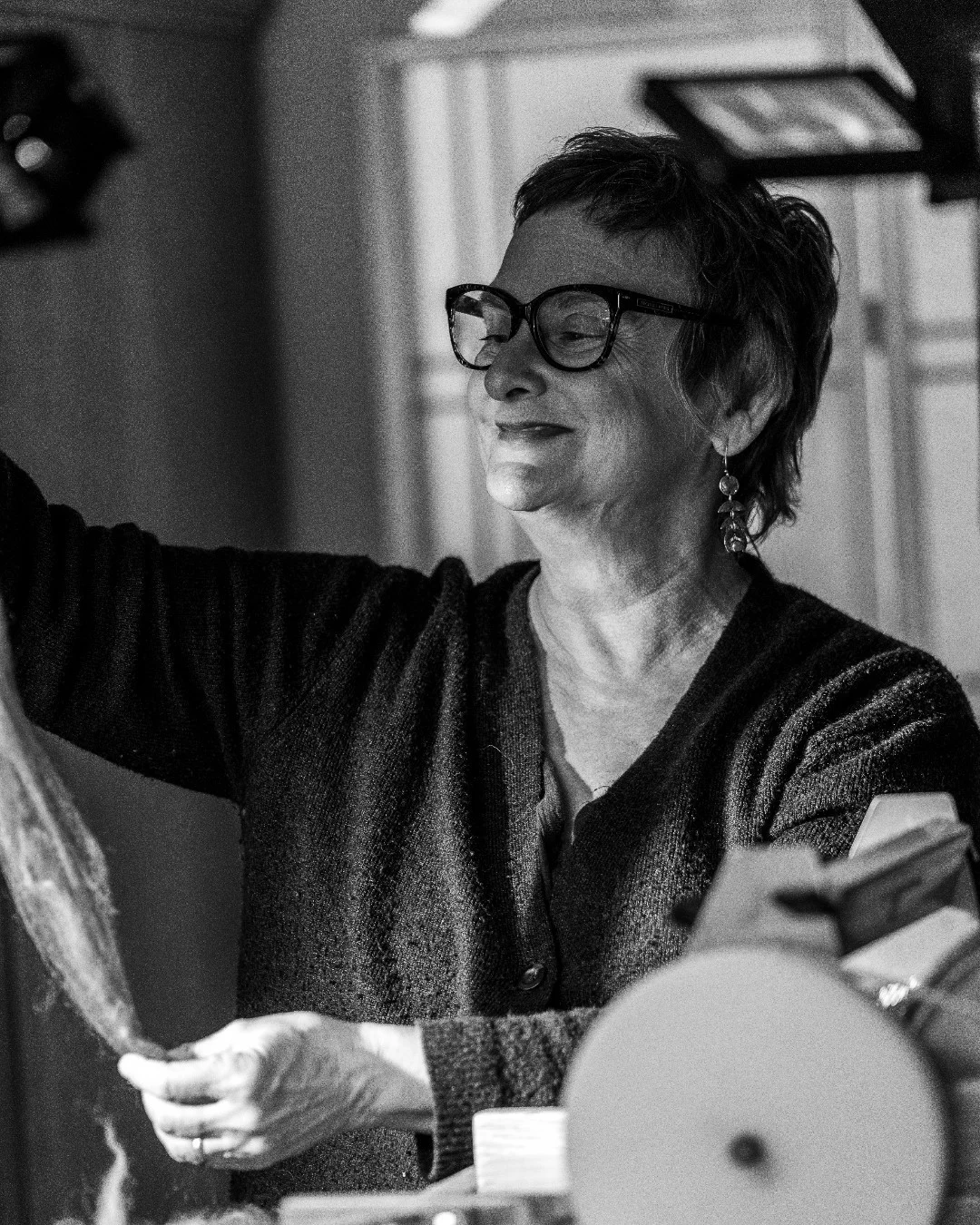 Susi Ryan lifts a sheet of felt beside a fiber-processing machine.