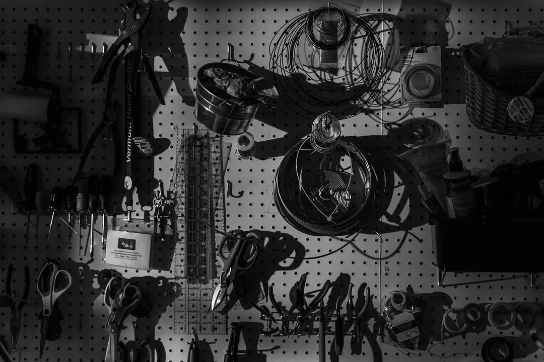A studio pegboard holds scissors, wire, rulers, and other fiber tools.