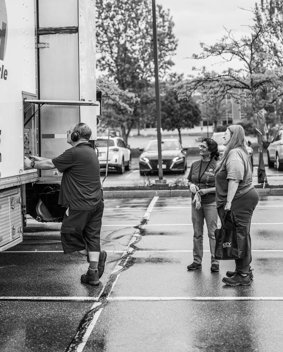 A worker rolls a document bin toward a shred truck while attendees wait nearby.