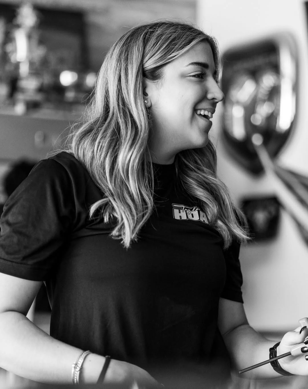 Black-and-white profile of Taylor Hoar smiling in the race shop.