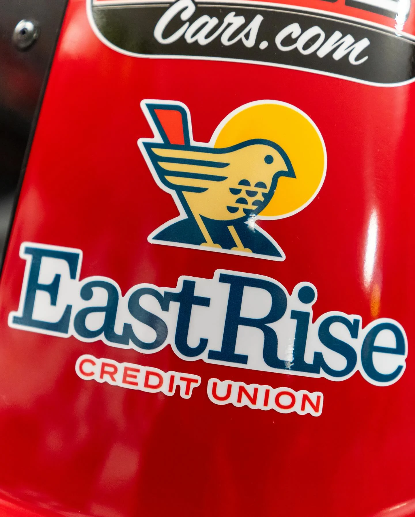 A close detail of the EastRise Credit Union logo on red race-car bodywork.