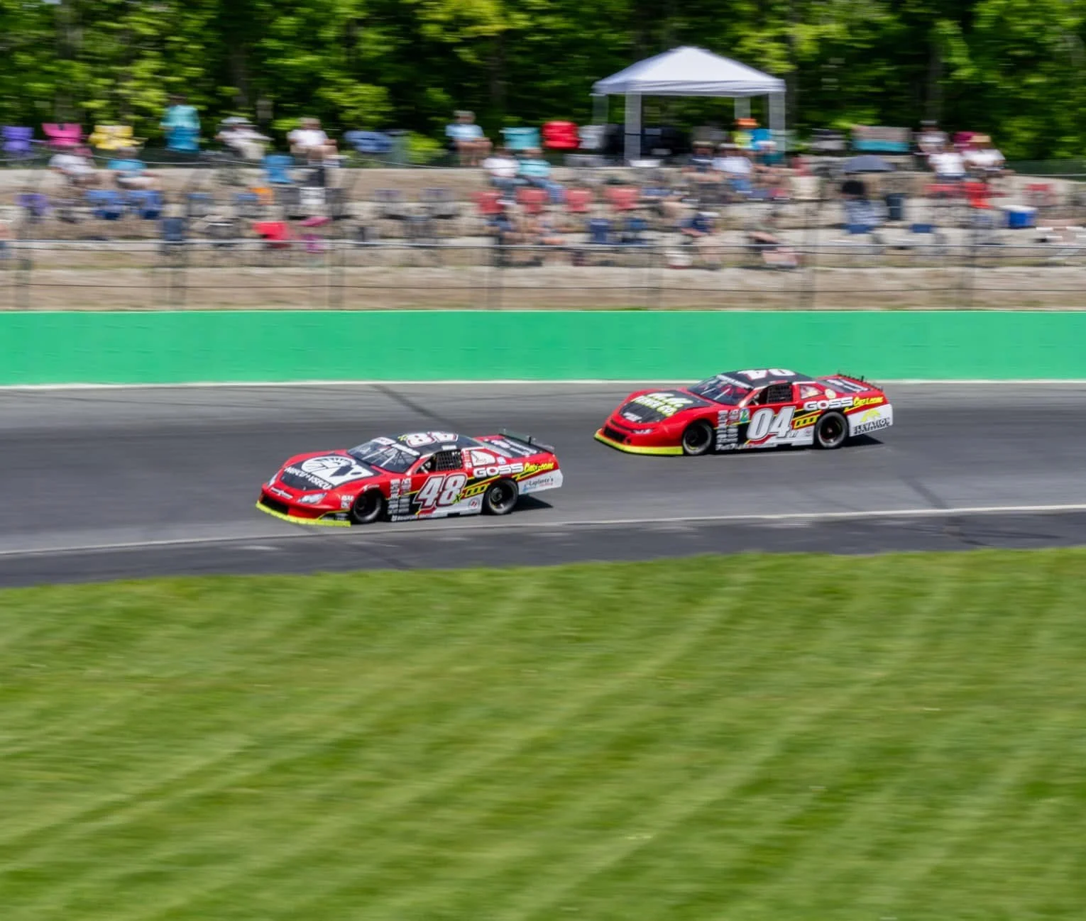 Taylor Hoar’s red No. 48x car leads the red No. 04 car past the green retaining wall.