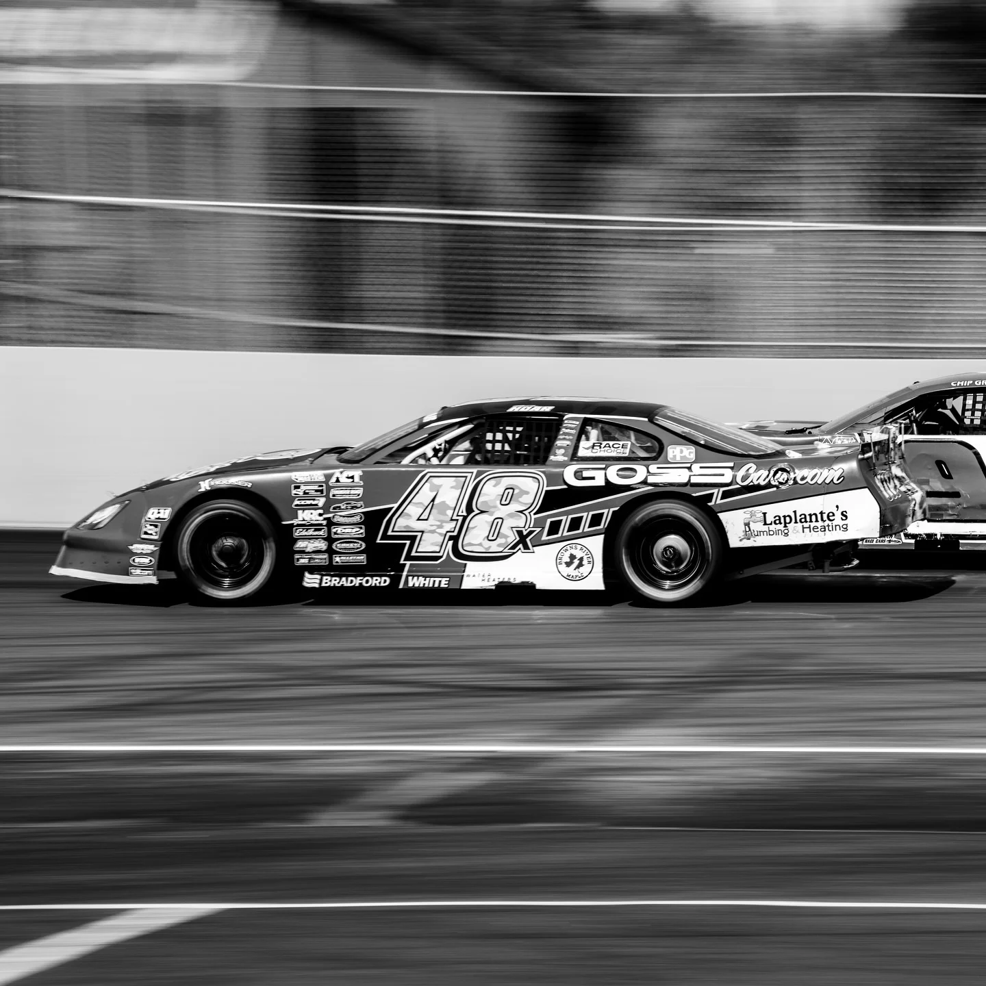 Black-and-white motion shot of Taylor Hoar’s No. 48x car racing beside another stock car.