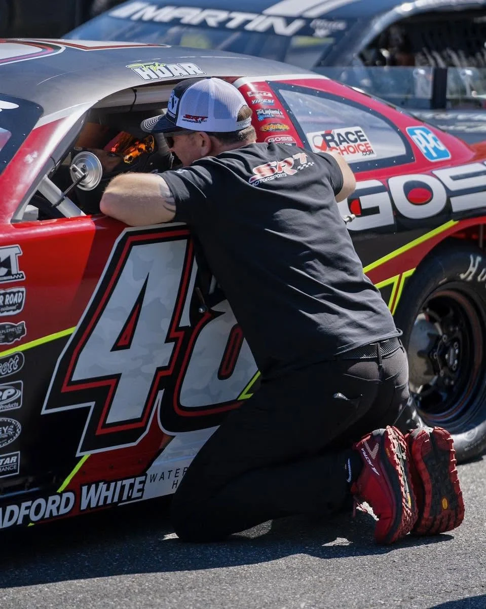 A crew member kneels and reaches through the window of Taylor Hoar’s No. 48 car.