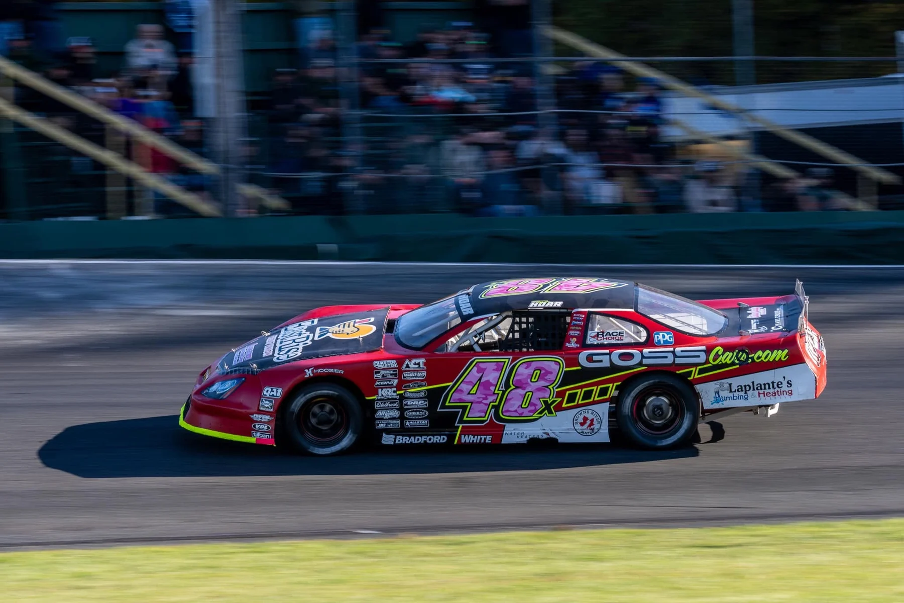 Taylor Hoar's No. 48x car, its number in pink camo, races past crowded grandstands at Thunder Road.