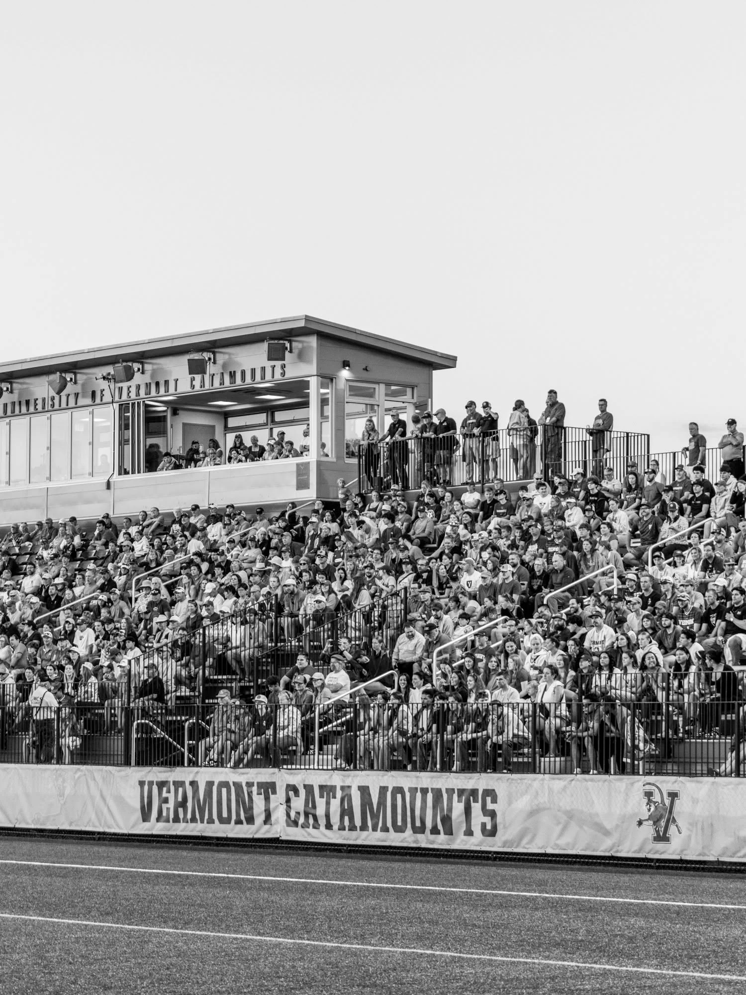 UVM men’s soccer players gather near a packed stand at Virtue Field.