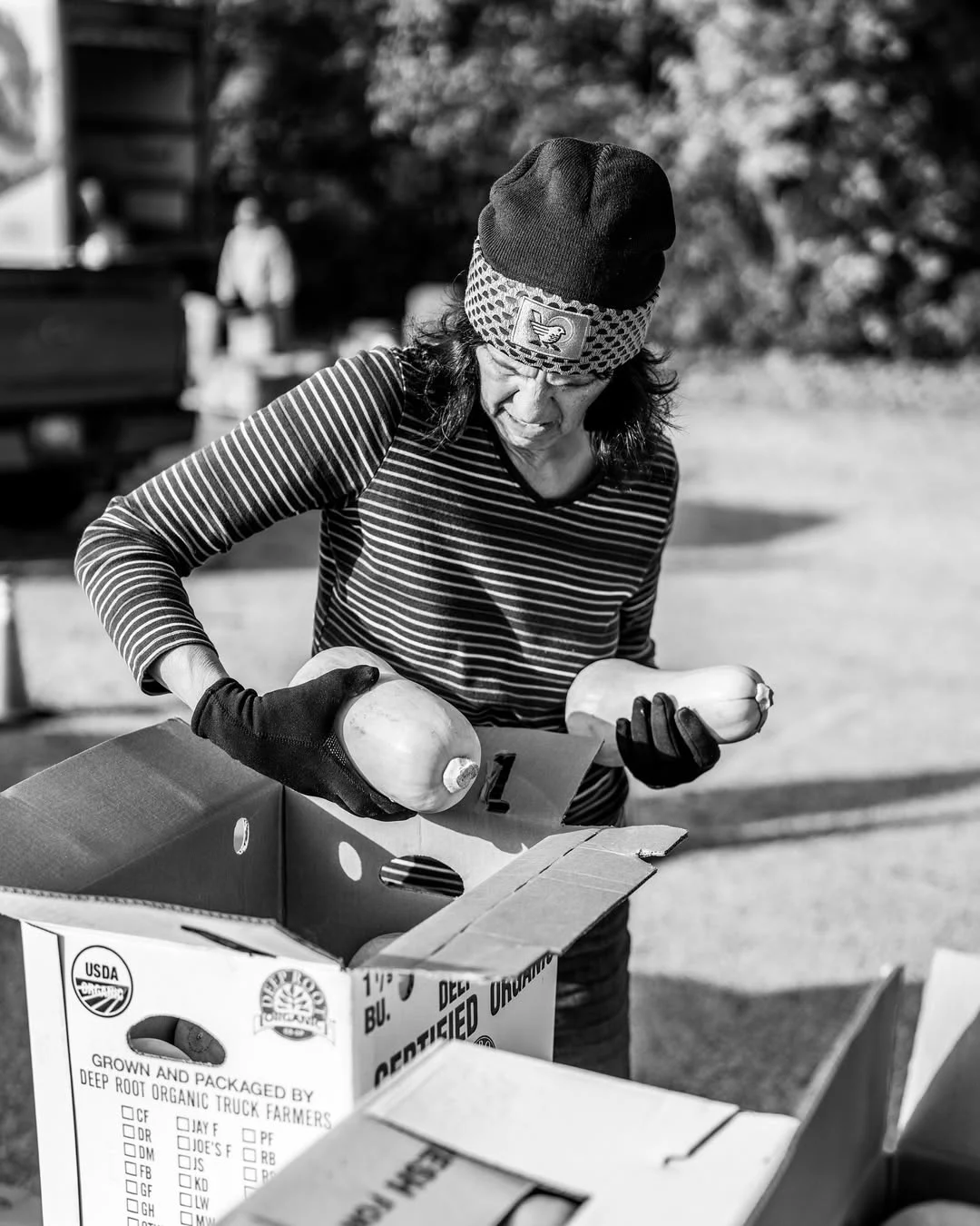 A volunteer packs vegetables into a cardboard box.