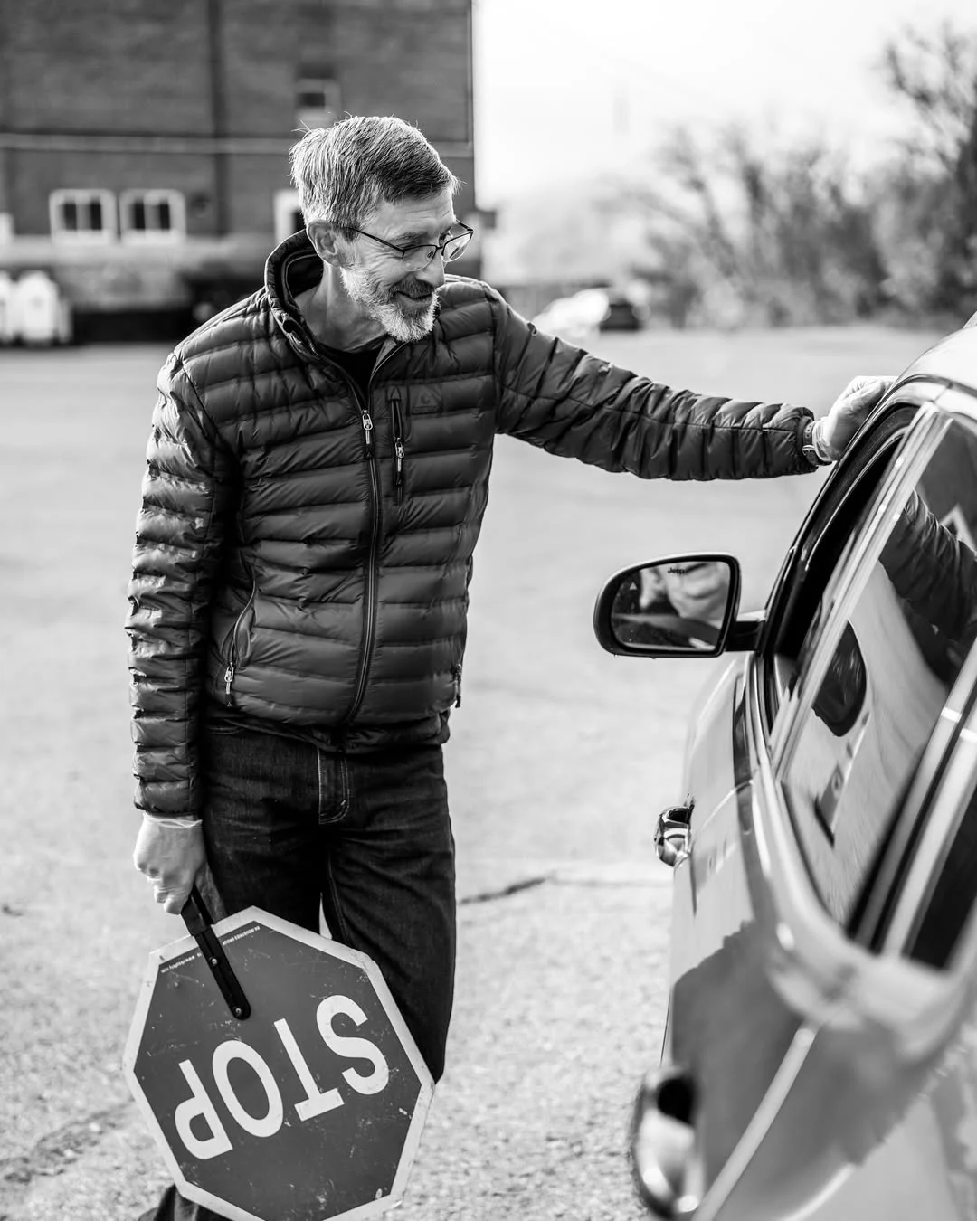A volunteer holding a stop sign directs a driver through the distribution line.