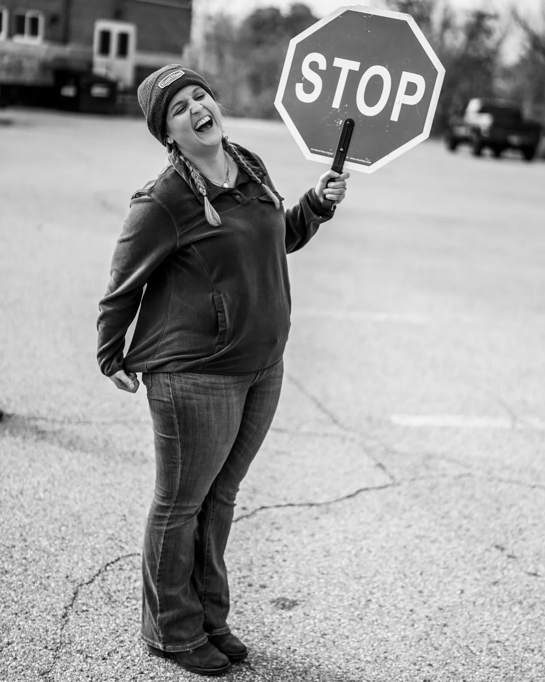 A volunteer raises a stop sign while calling toward approaching vehicles.
