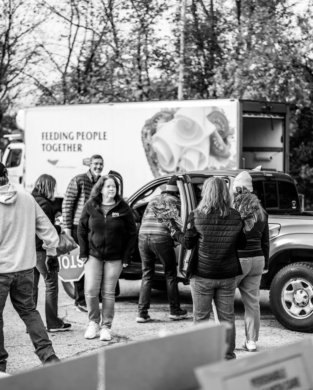 Volunteers gather beside a food bank truck at a produce distribution.