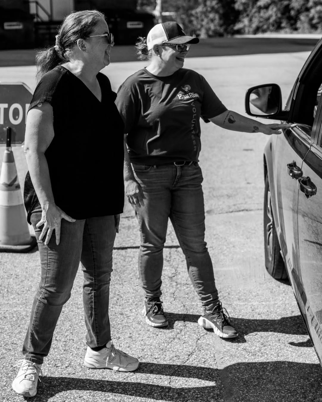 Two volunteers guide a driver through a produce distribution line.