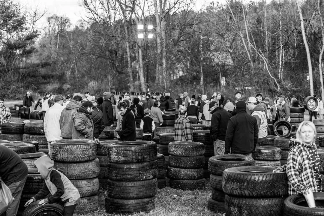 Volunteers gather among rows of stacked tires at an outdoor collection.