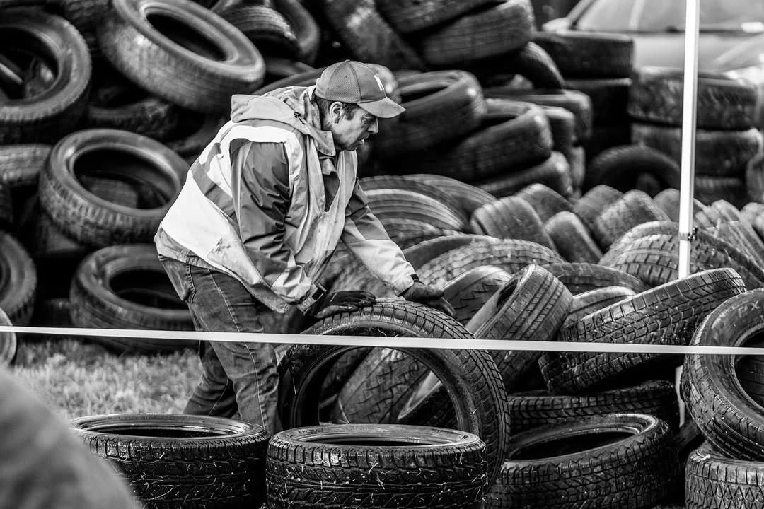 A volunteer sorts tires from a large pile.
