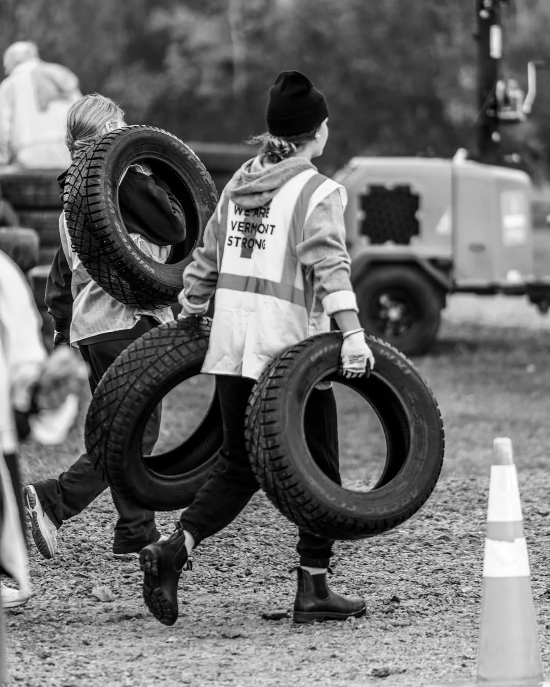 A volunteer carries three tires across the collection site.