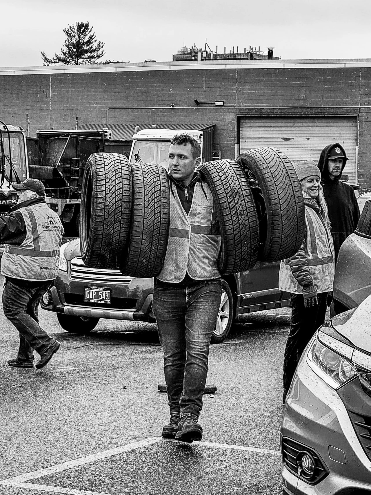 A volunteer carries a stack of tires across the collection site.