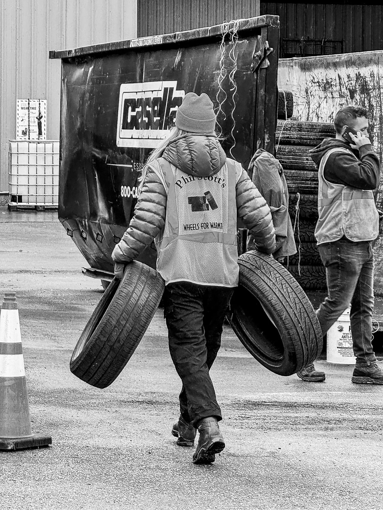 A volunteer carries two tires past the collection warehouse.