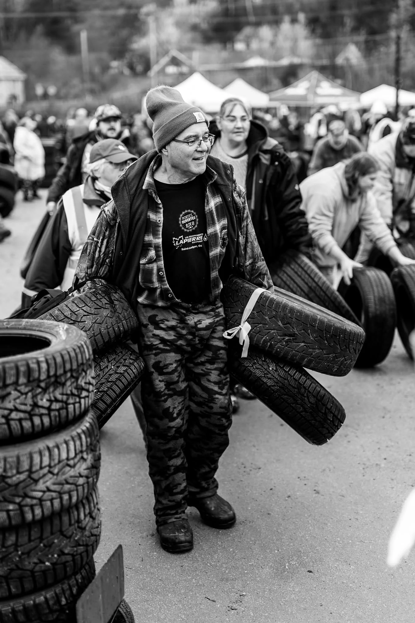 A volunteer stacks tires among rows collected for Wheels for Warmth.