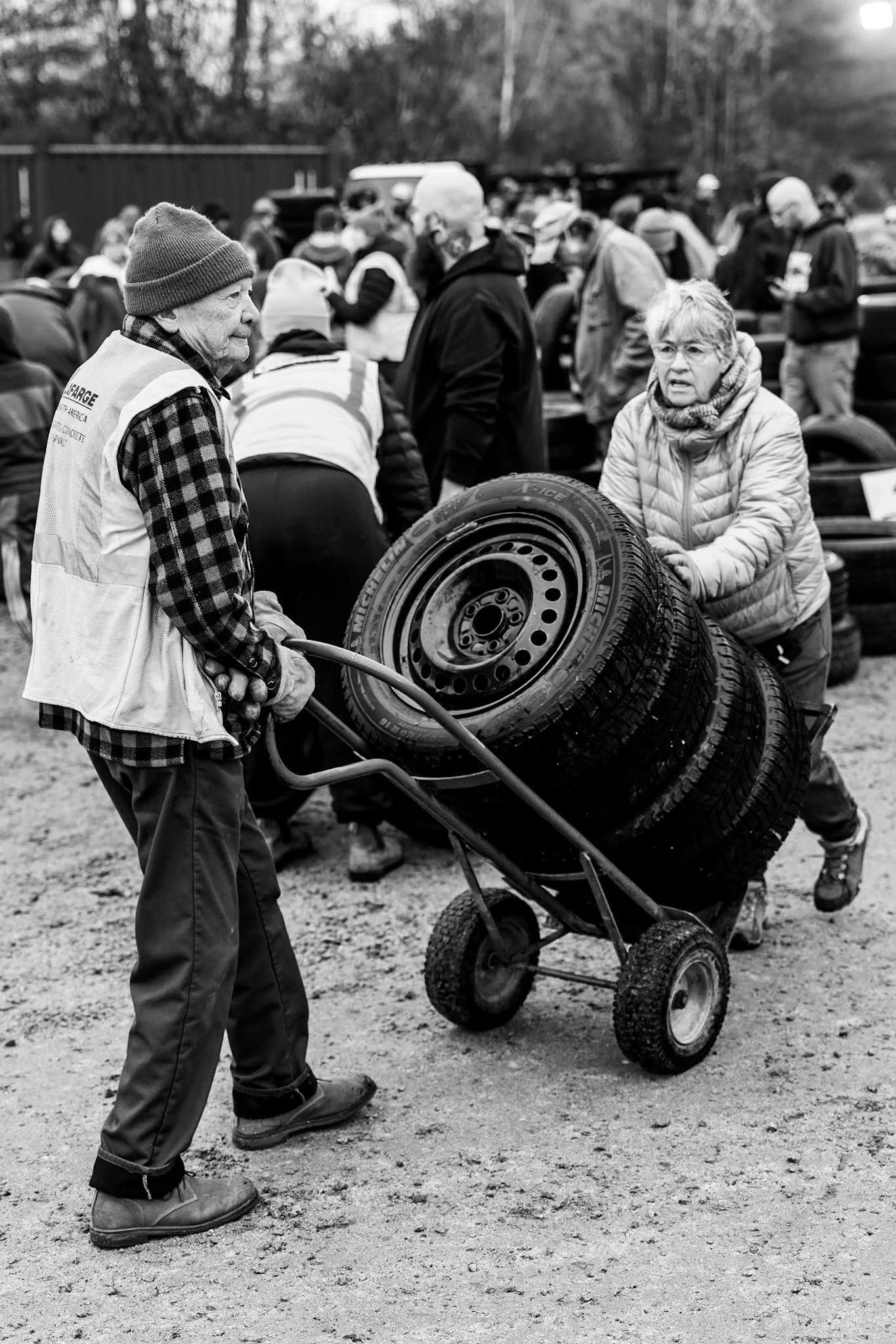 A volunteer carries tires through a crowded Wheels for Warmth collection site.