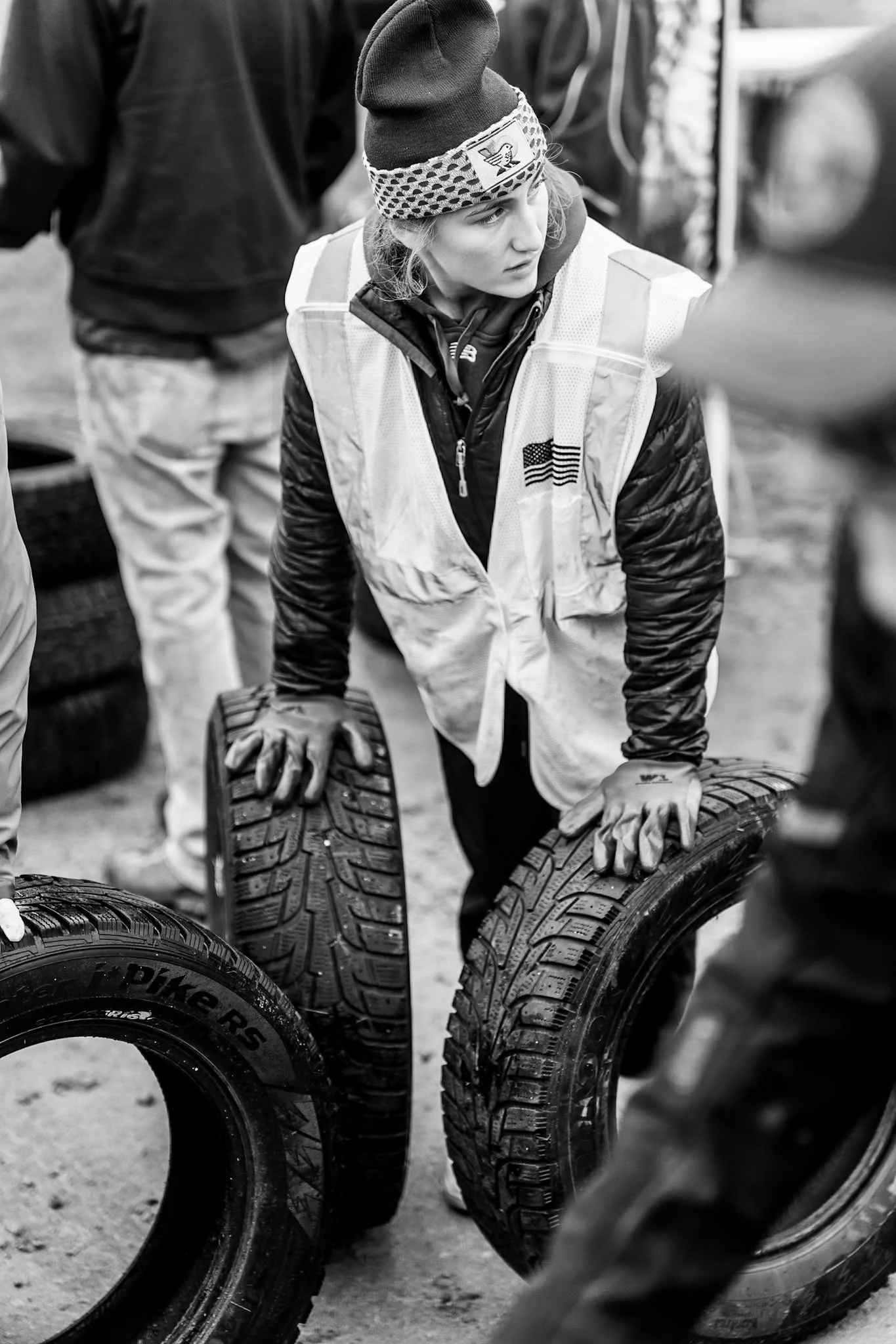 A volunteer kneels while handling a tire at Wheels for Warmth.