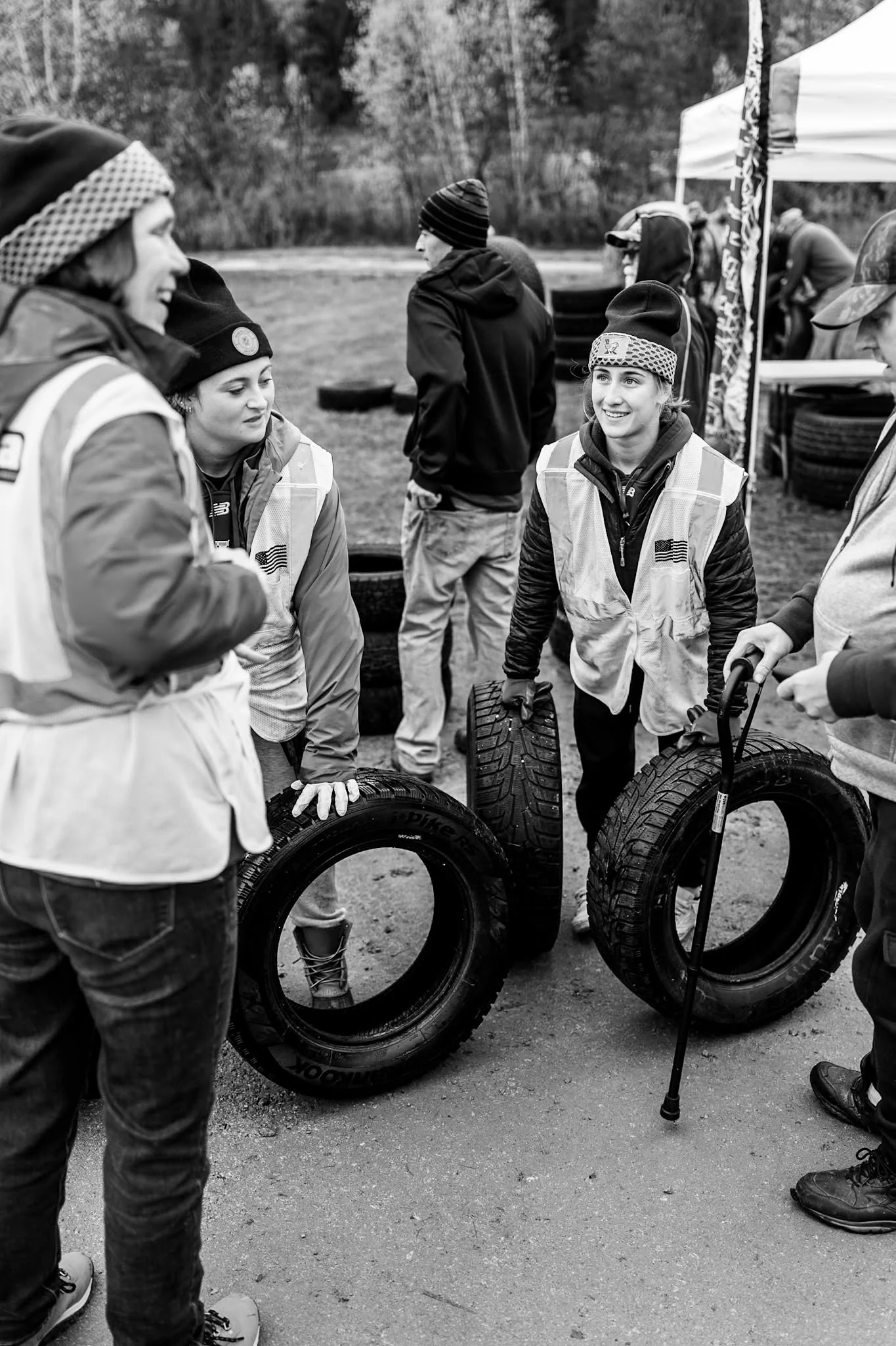 A volunteer in a safety vest carries two tires at Wheels for Warmth.