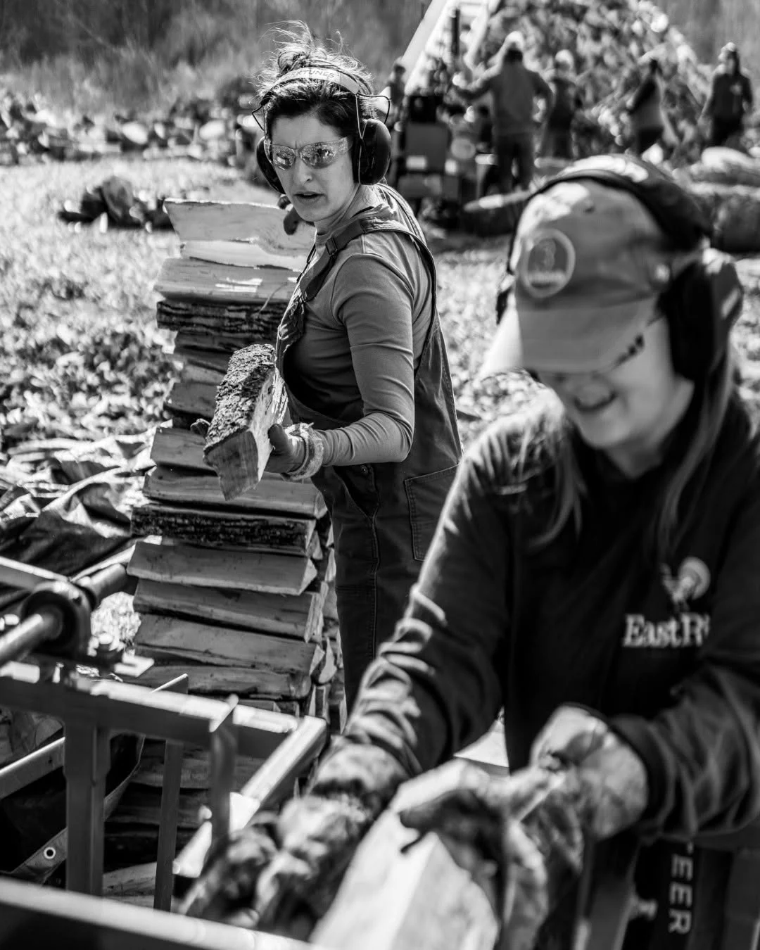 Two volunteers sort split logs at a processing table.