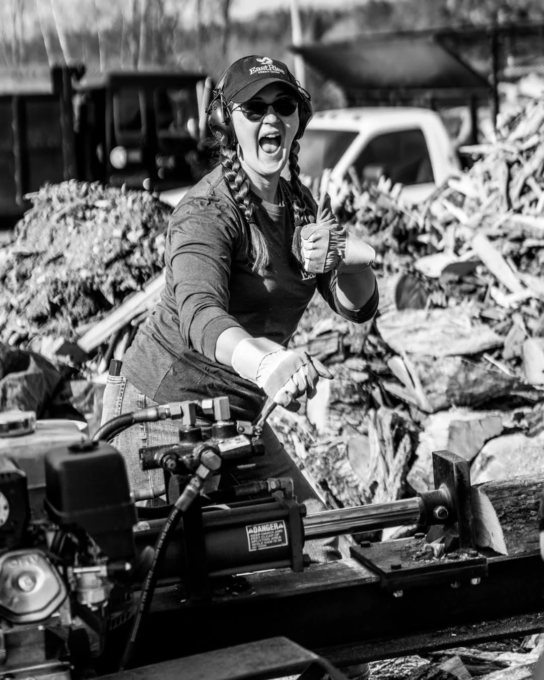 A volunteer gives a thumbs-up while operating a log splitter.