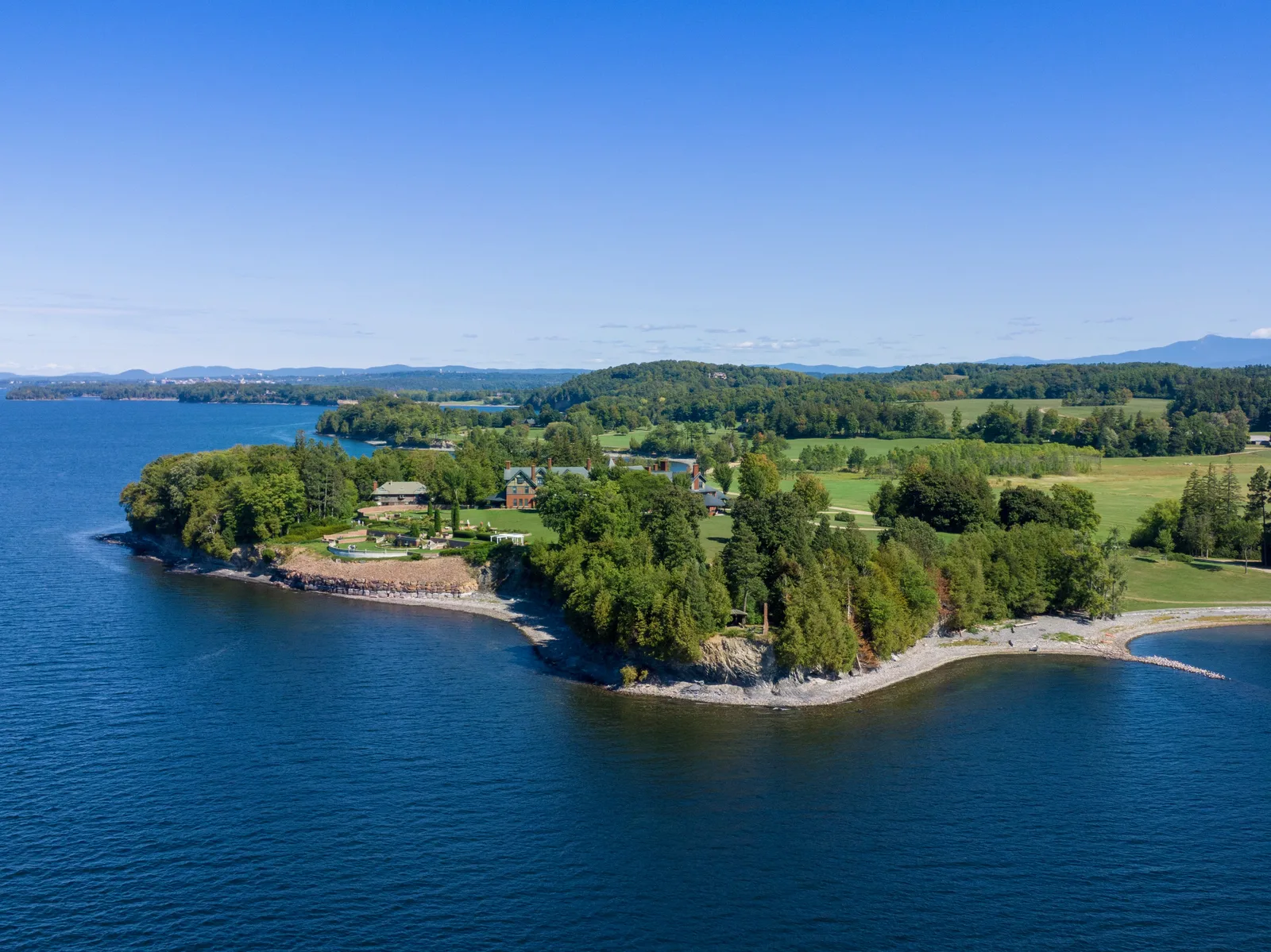 Wooded peninsula with gardens and buildings extending into a deep blue lake