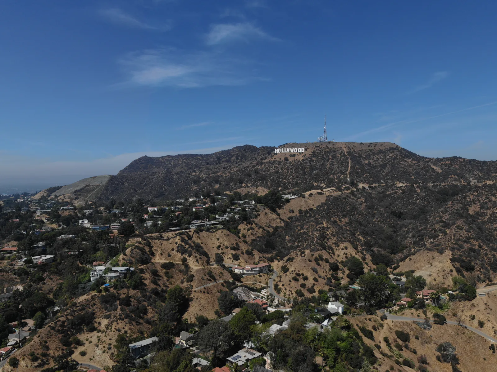Hollywood Sign on a dry hillside with Los Angeles neighborhoods below