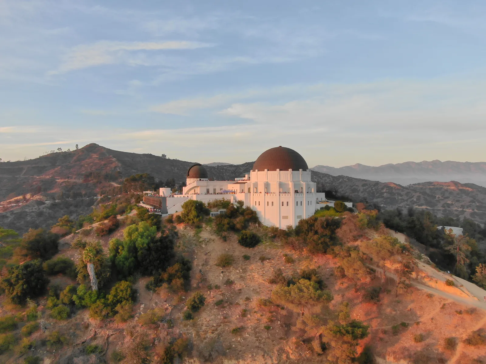 Griffith Observatory on its hillside with mountains and city neighborhoods beyond