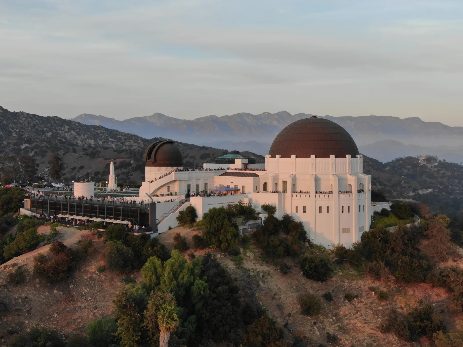 Close aerial view of Griffith Observatory against layered mountain ridges