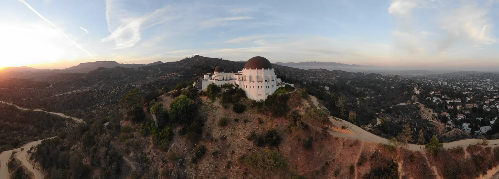 Wide sunset panorama of Griffith Observatory, winding roads, and Los Angeles hills