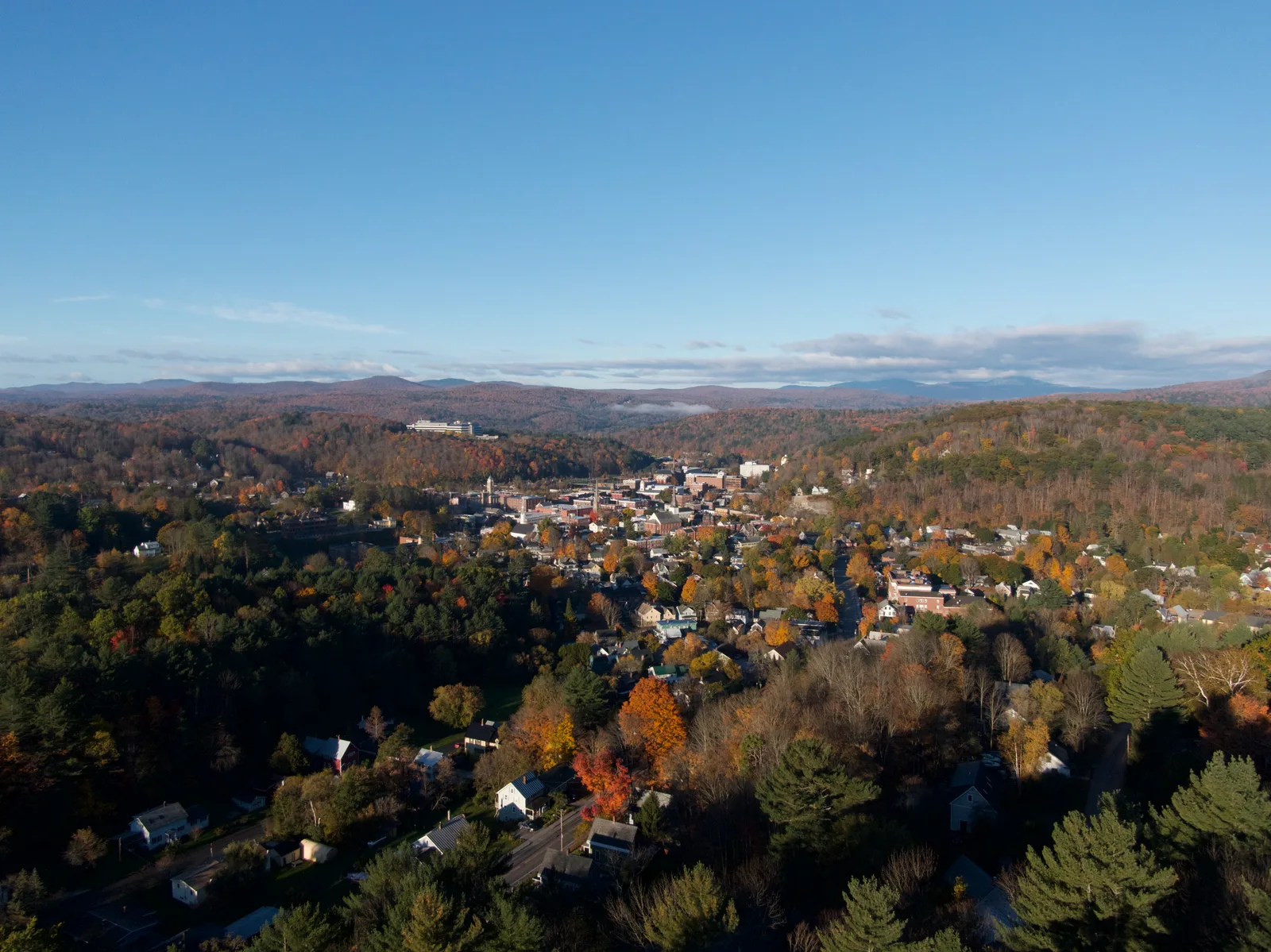 Aerial view of a small town in a valley surrounded by late-autumn hills
