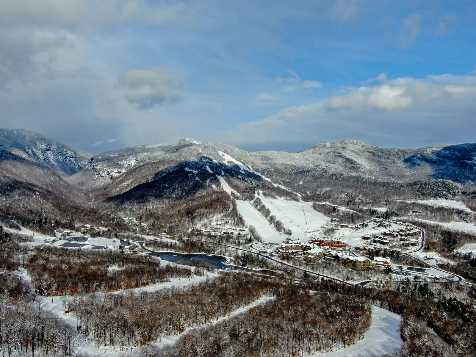 Snow-covered mountain valley with ski trails, buildings, and winding roads