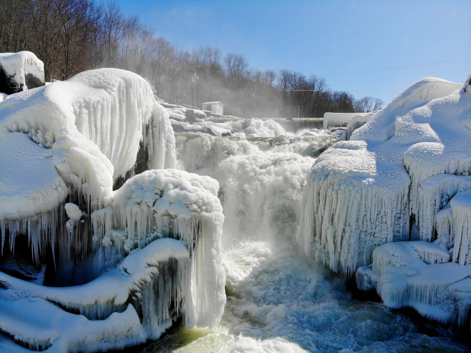 Frozen waterfall cascading between thick shelves of ice and snow-covered rocks