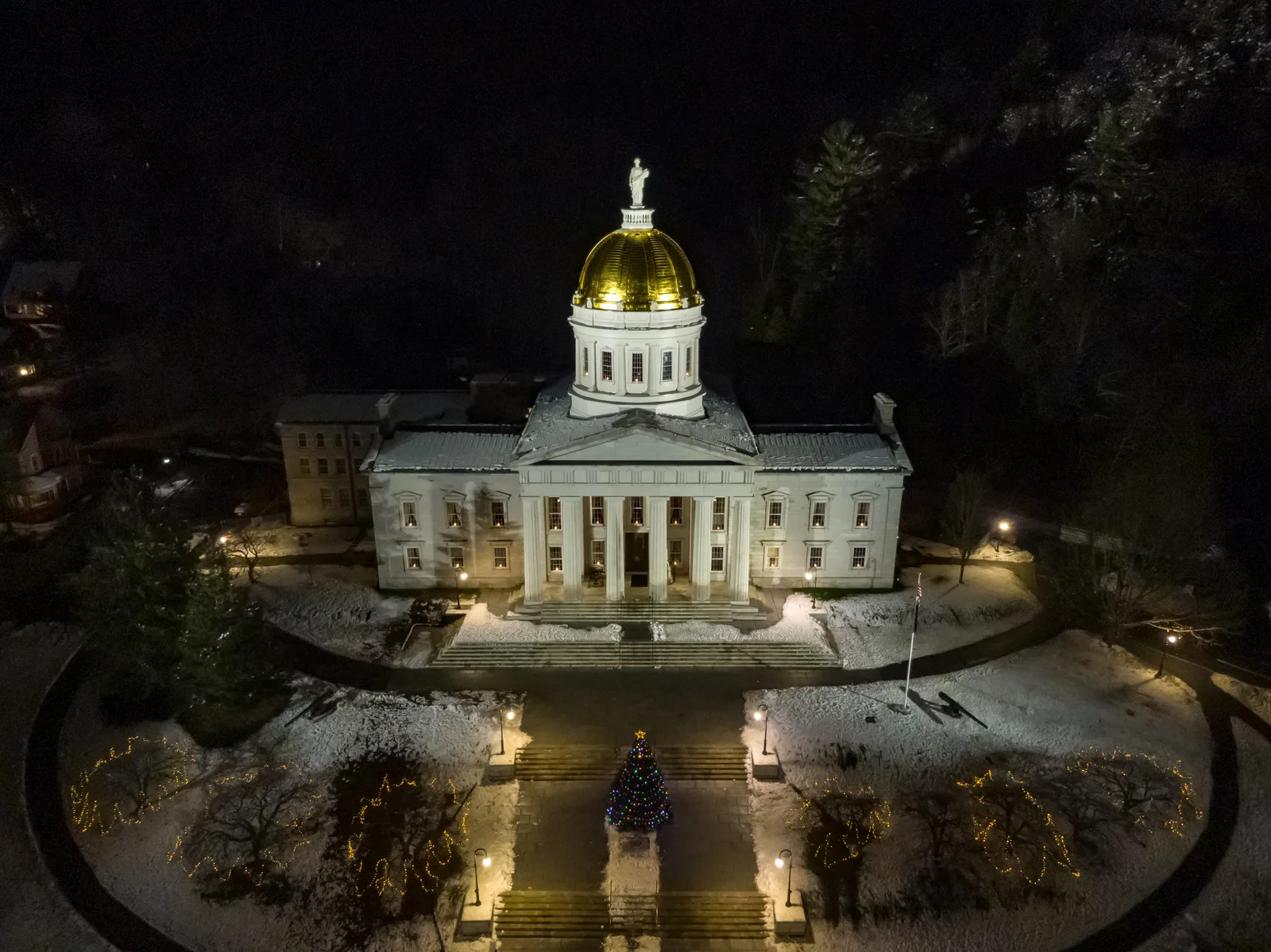 Vermont State House illuminated at night amid snow-covered grounds