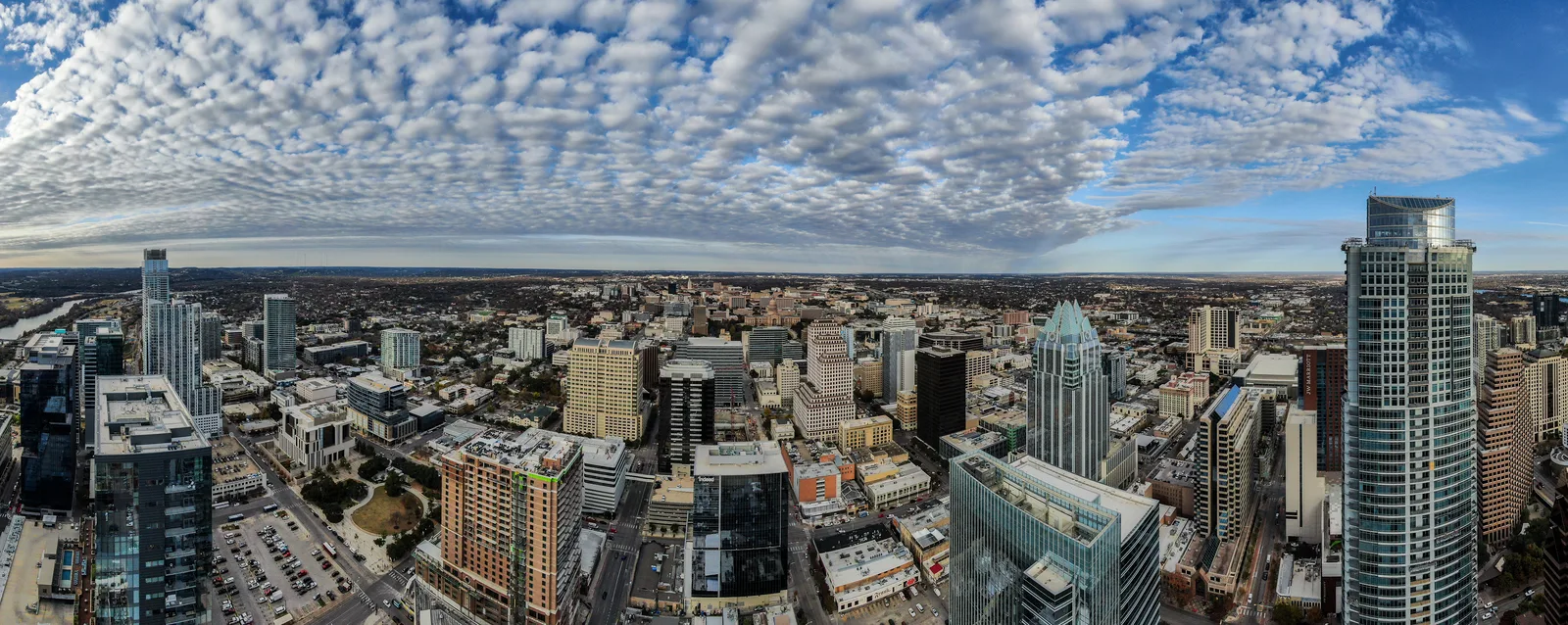 Wide aerial panorama of downtown Austin towers under rows of textured clouds