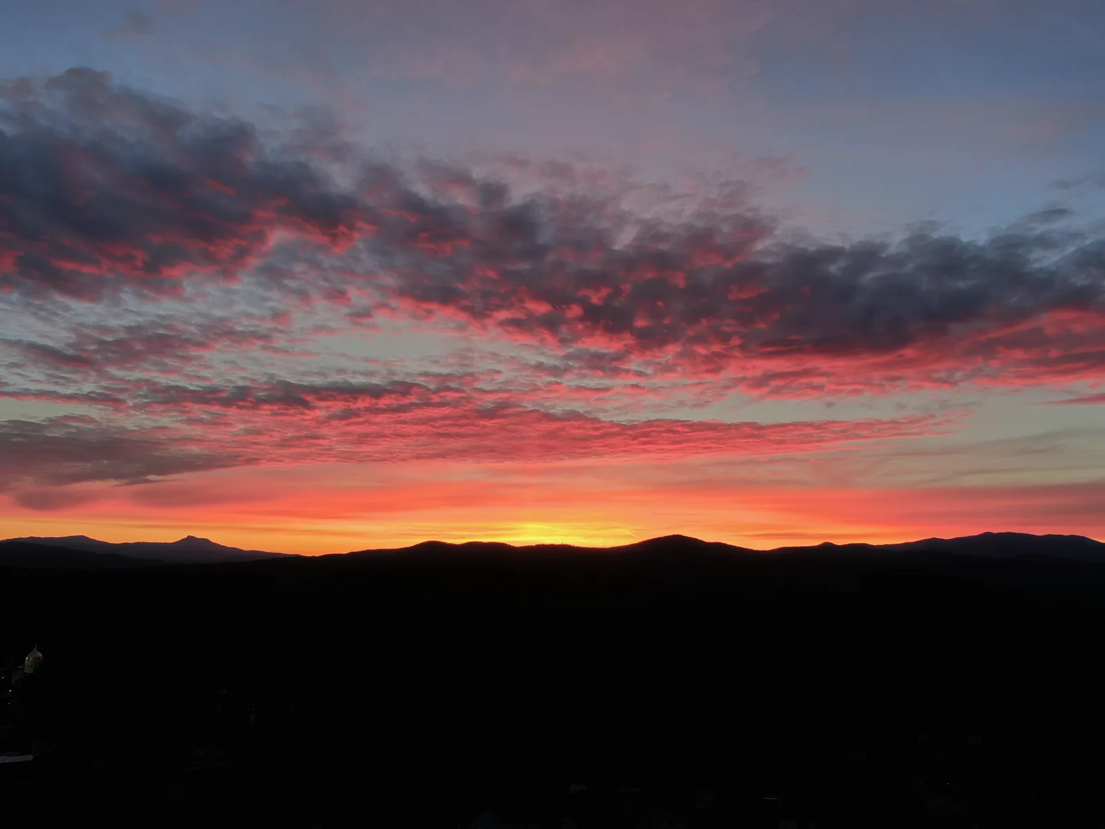 Red and orange sunset glowing above a dark silhouette of distant mountains