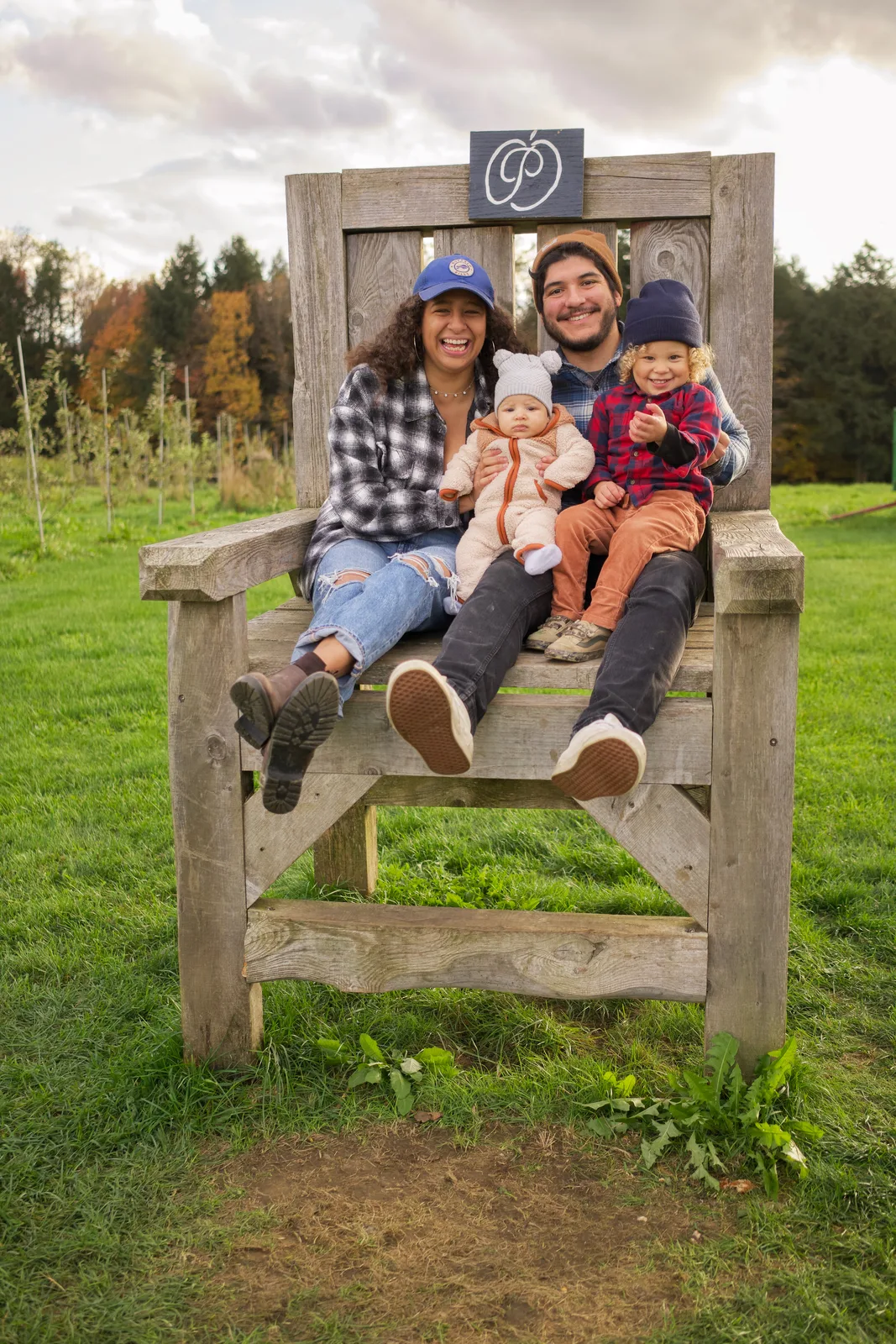 Four people on wooden chair, sunset lighting on grassy field and trees