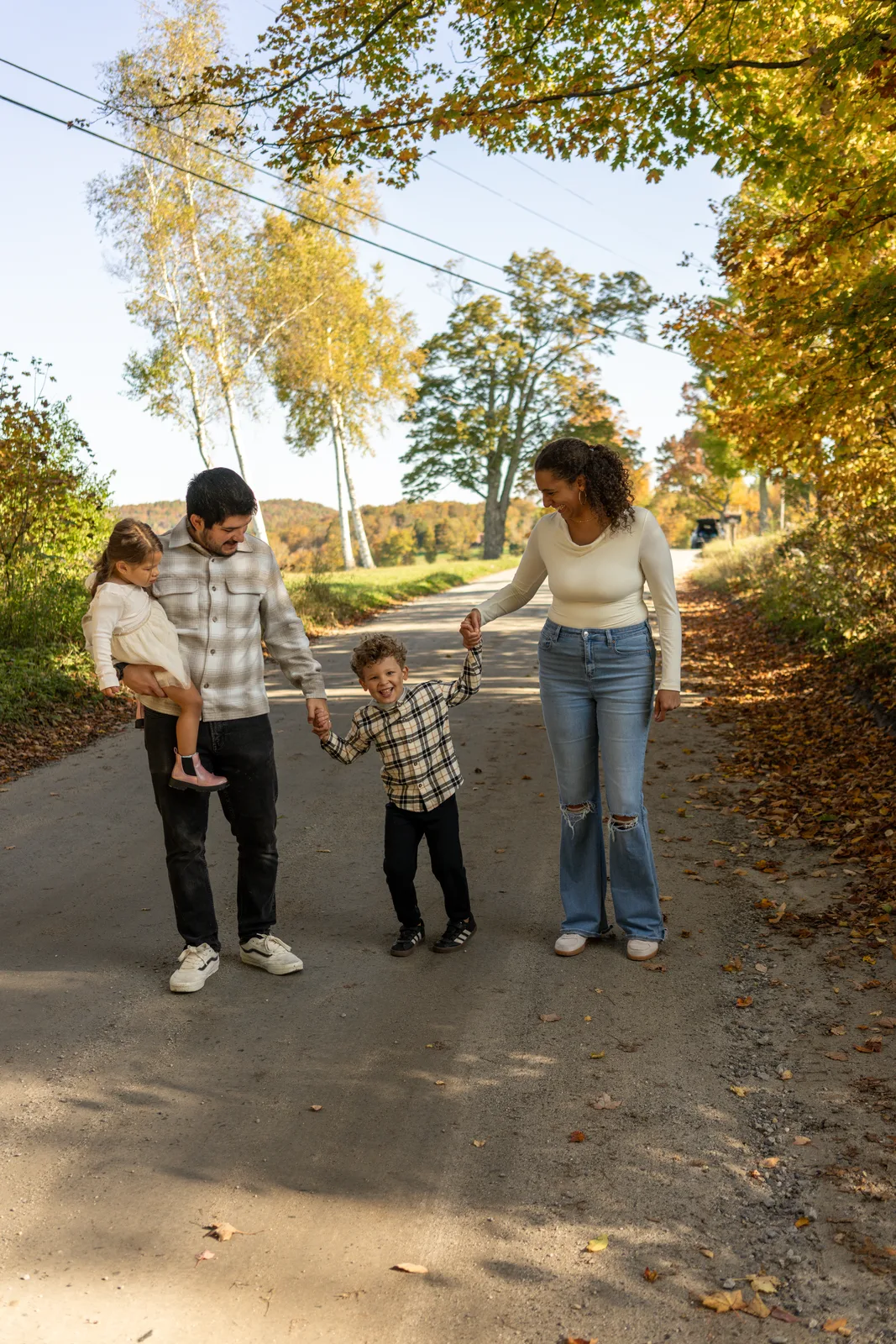 Four people walking on a paved path, two adults holding hands with two children