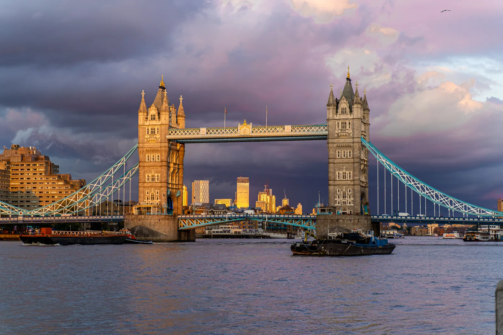 Tower Bridge spanning the River Thames as late sunlight breaks through dark clouds