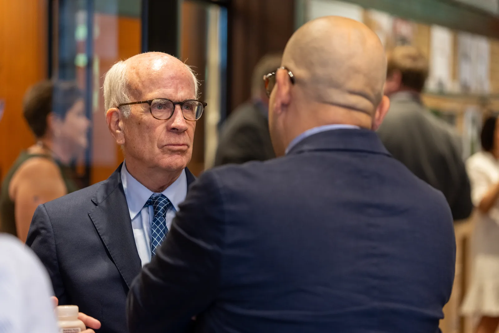 A delegate wearing glasses speaks with another attendee during the morning arrival.