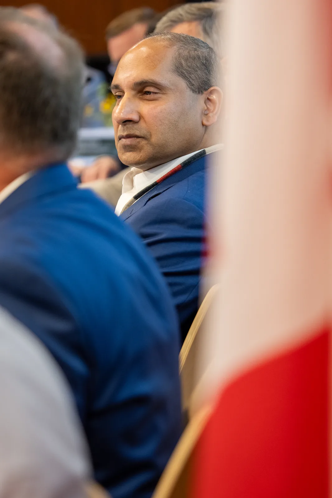 A delegate listens across the table with a Canadian flag filling the foreground.