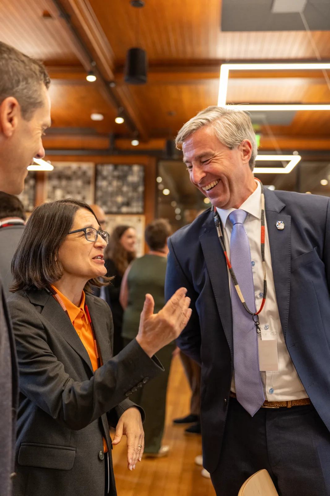 A woman speaks with a tall suited delegate during a break inside the Coach Barn.