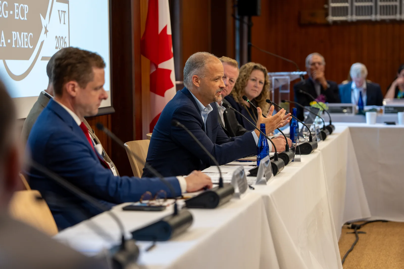 A seated delegate gestures while speaking at the head of the conference table.
