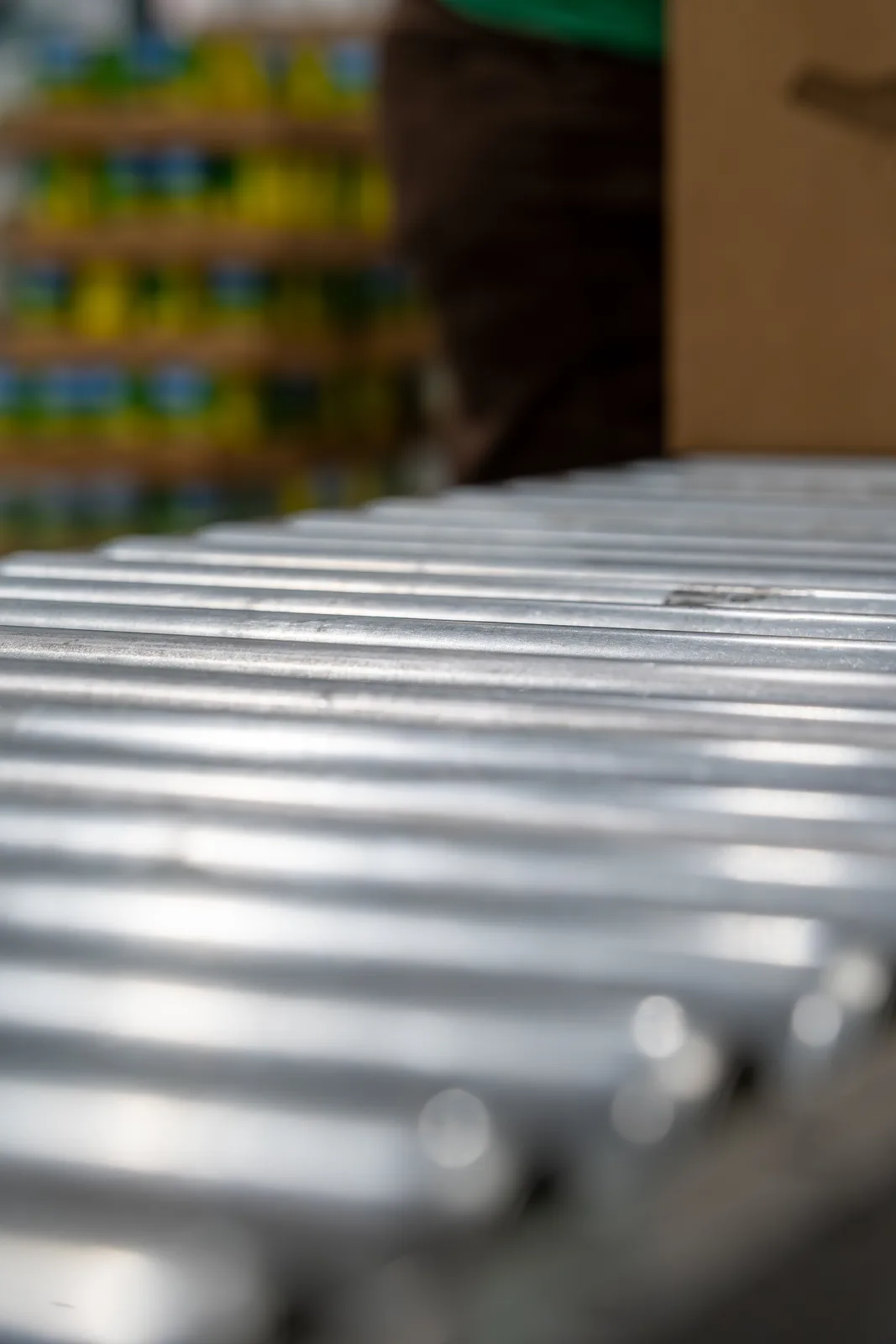 Close-up of corrugated metal surface with blurred warehouse background and colorful shelves