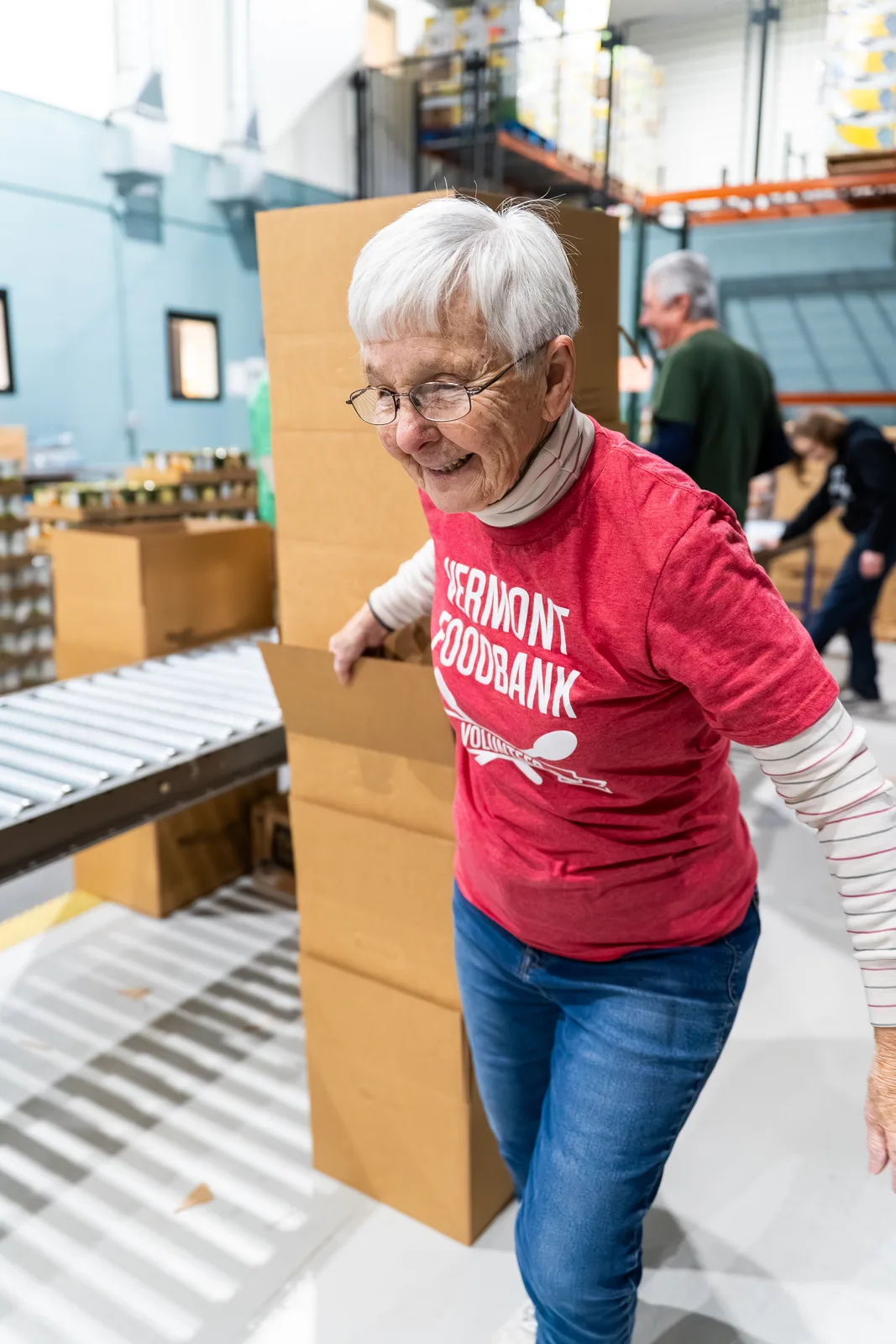 Person in red shirt pushing a cardboard box on conveyor in warehouse