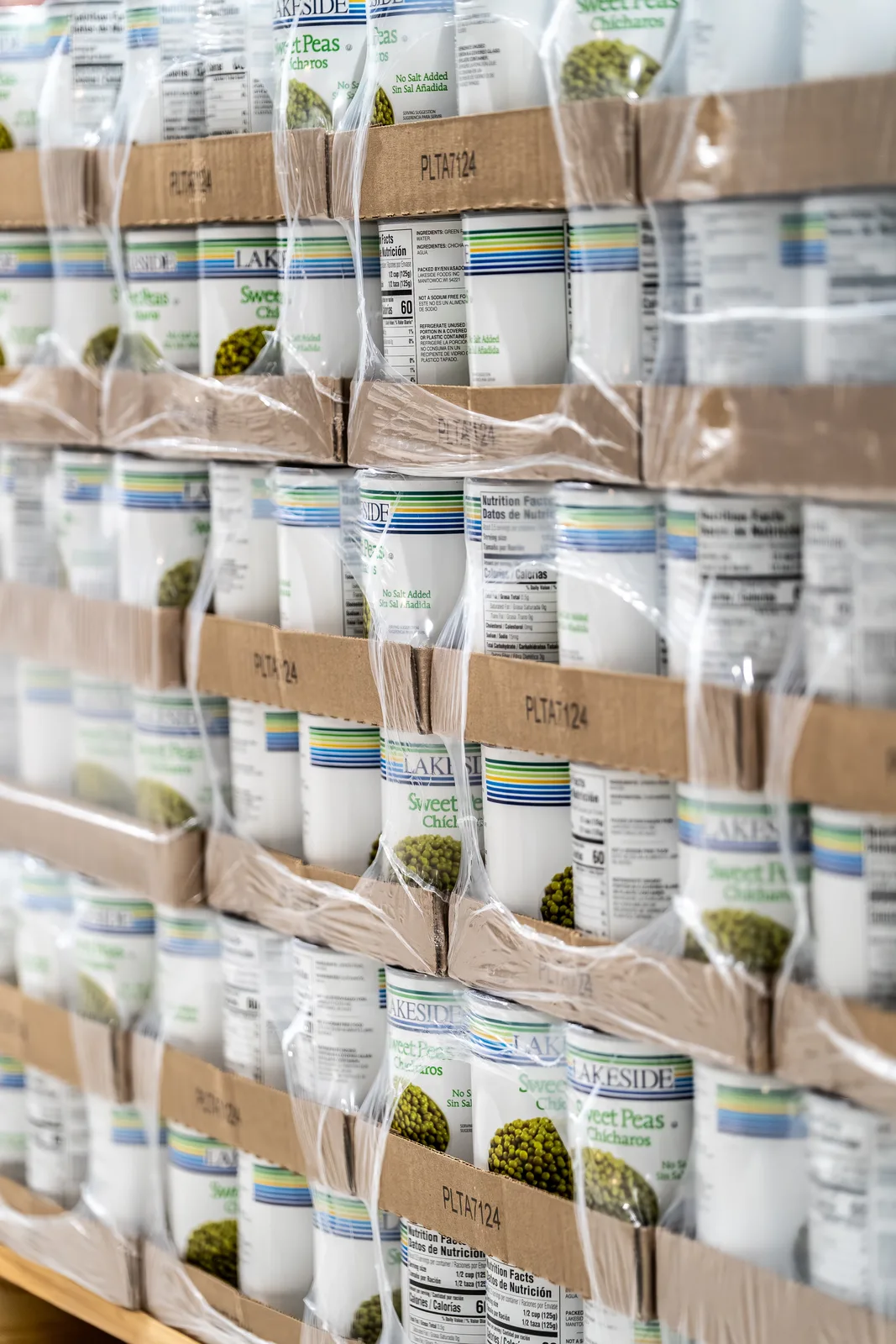 Plastic-wrapped boxes of canned sweet peas stacked on warehouse shelves