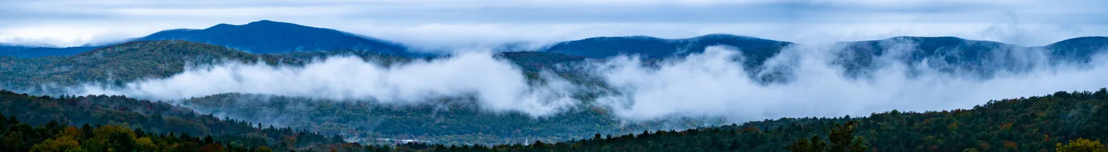 Panoramic view of forested Vermont ridges partly covered by long bands of fog