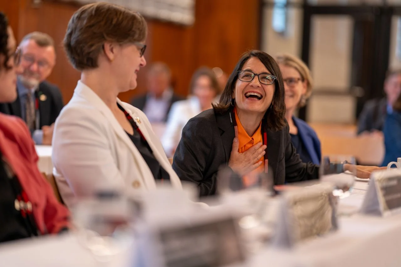 A smiling delegate in an orange blouse reacts during a conference discussion.